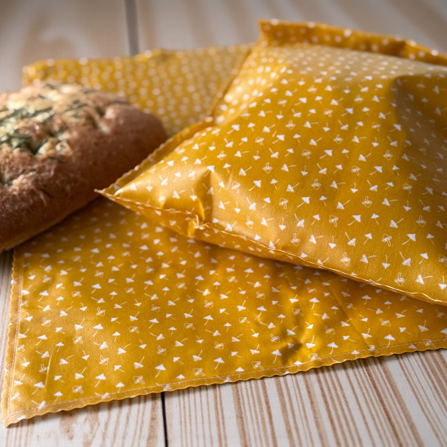 Yellow patterned fabric with a loaf of bread on a wooden surface