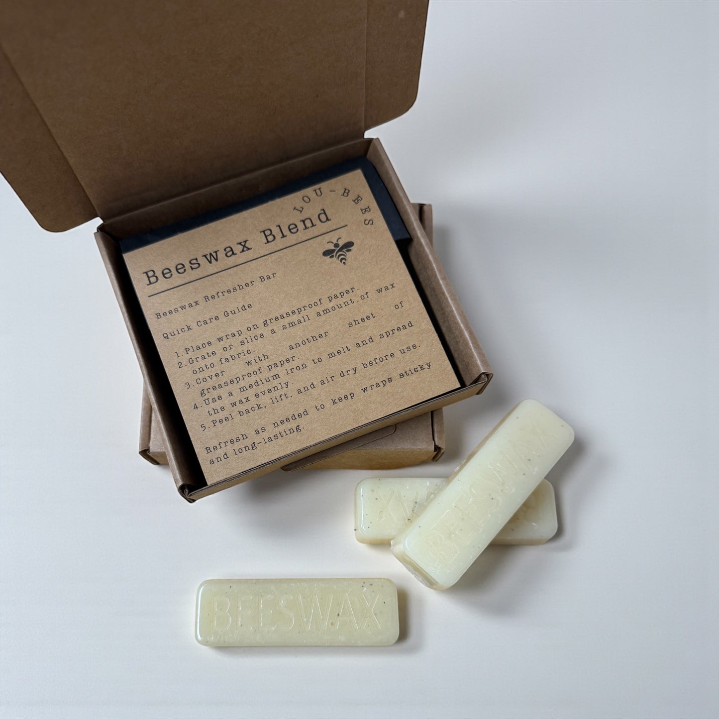 Beeswax blend bars with an open box containing a label on a white background