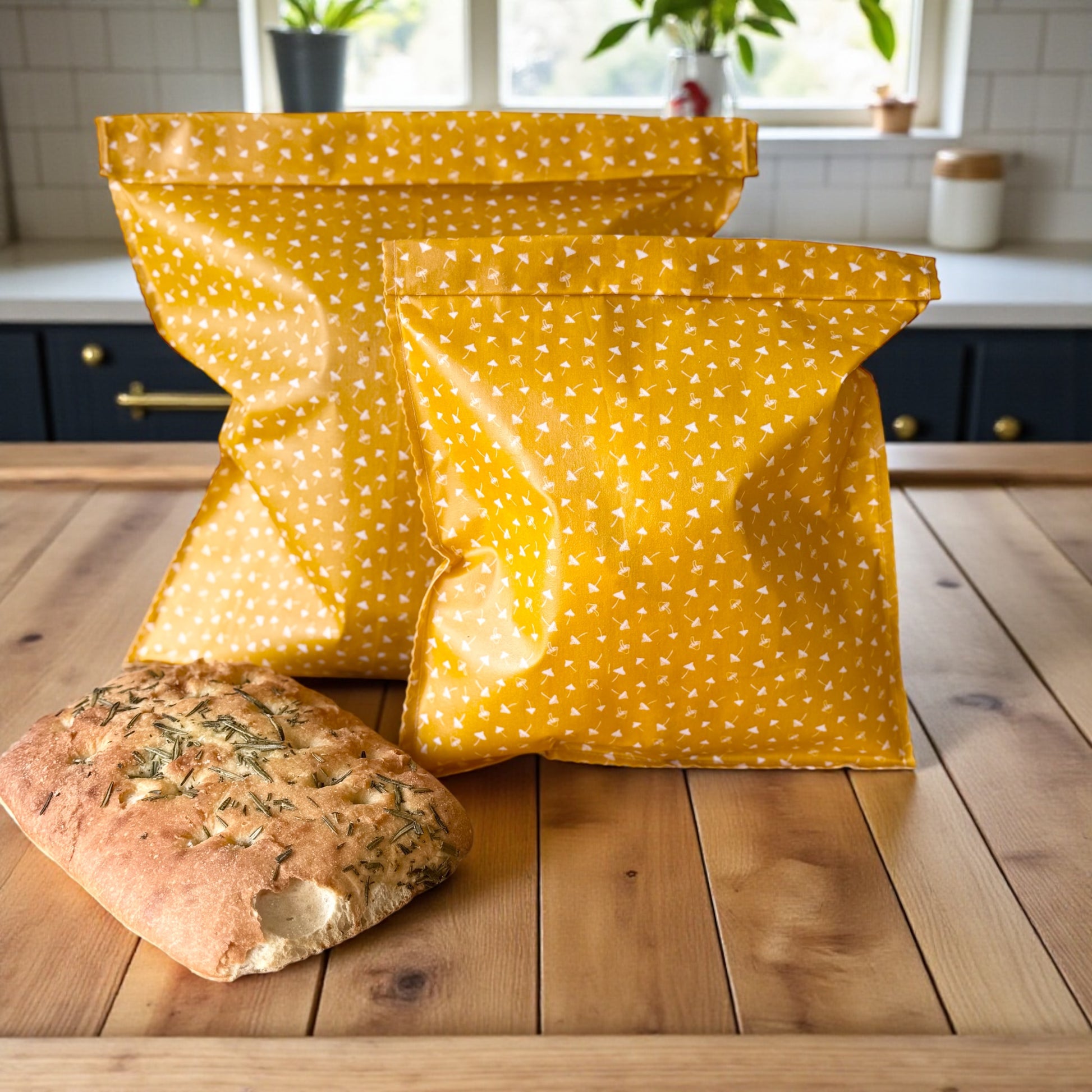 Two yellow polka dot bags on a wooden table with bread in a kitchen setting.