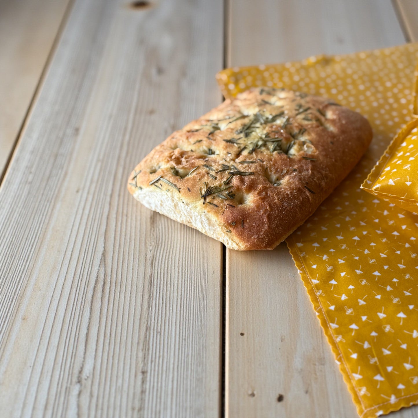 Loaf of bread on a wooden surface with a yellow patterned cloth underneath